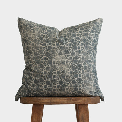 Gray and cream damask patterned throw pillow displayed on a wooden stool.