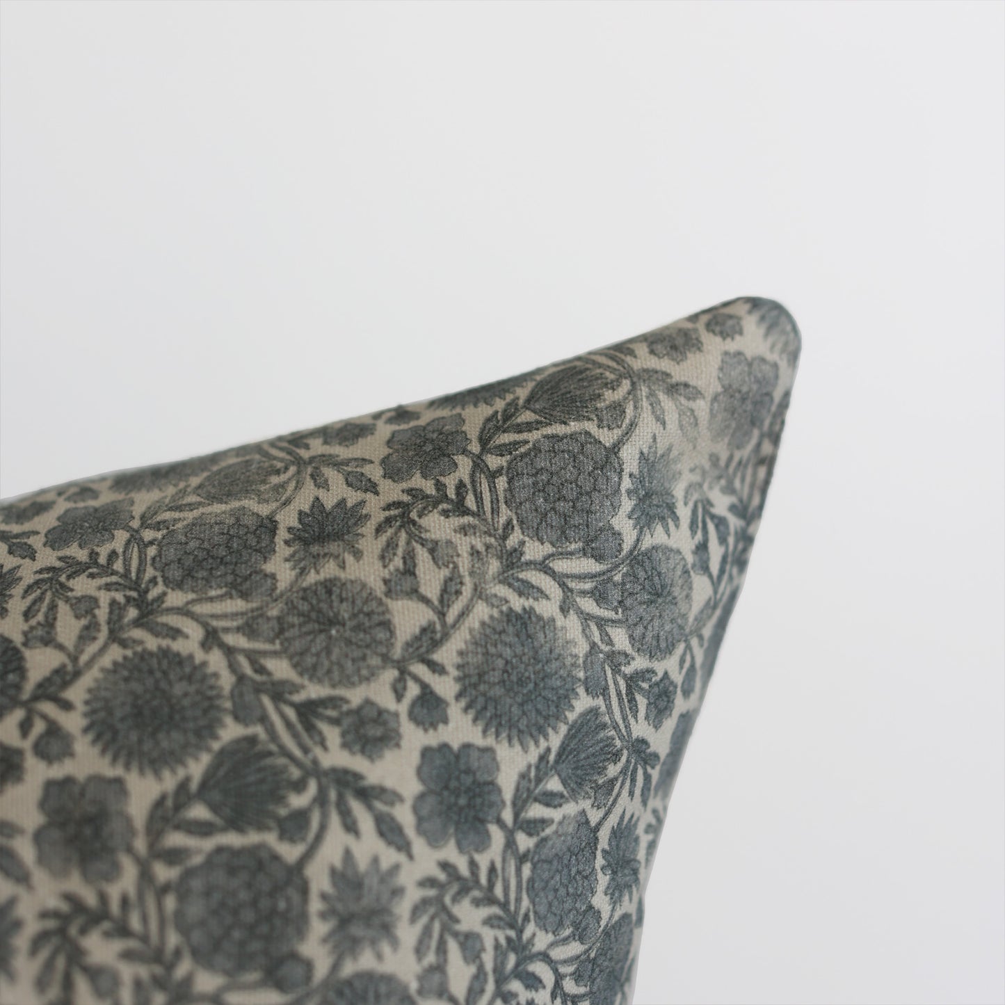 Blue and cream floral patterned pillow corner with botanical leaf design.