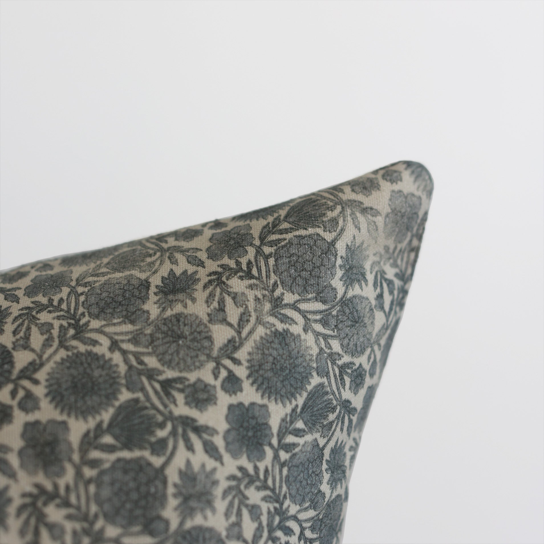 Blue and cream floral patterned pillow corner with botanical leaf design.