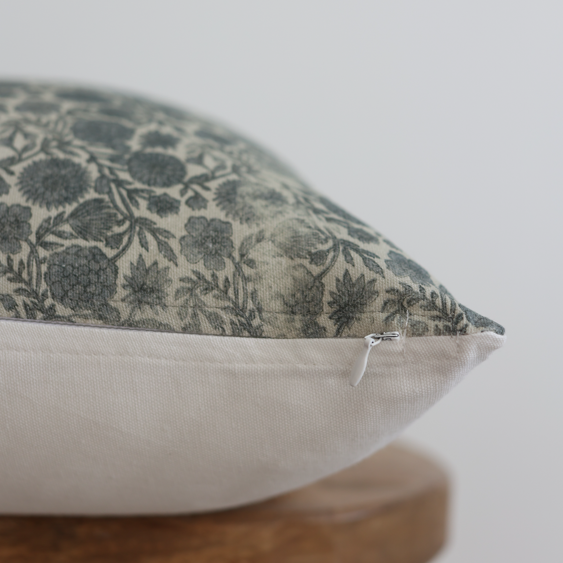 Rectangular pillow with blue and cream floral pattern on top half and cream solid fabric on bottom half, featuring a zipper c