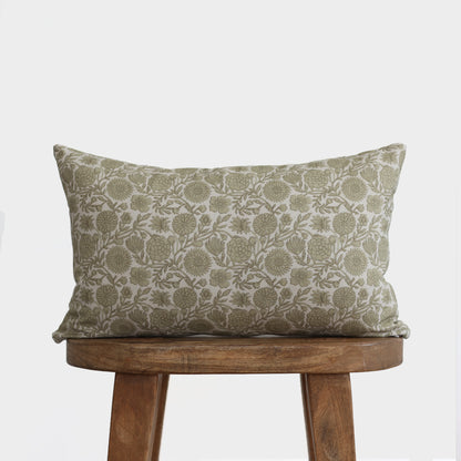 Green and cream lumbar pillow with floral botanical print, displayed on wooden stool.