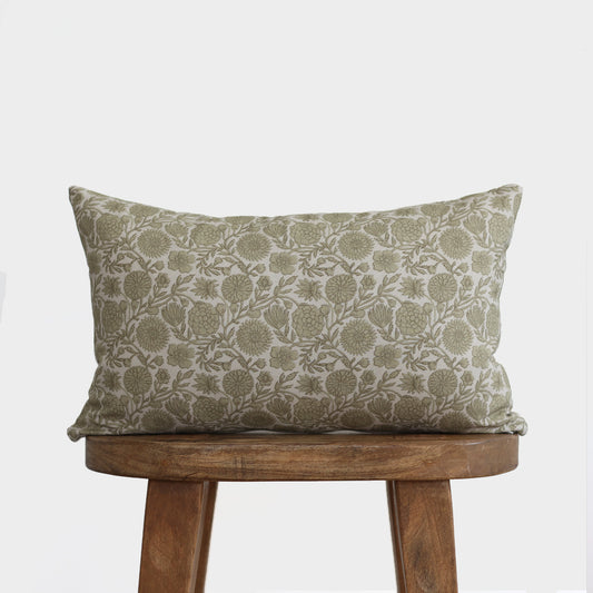 Green and cream lumbar pillow with floral botanical print, displayed on wooden stool.