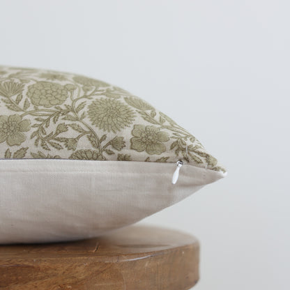 Green and cream floral patterned lumbar pillow with solid cream back and zipper closure, displayed on wooden base.