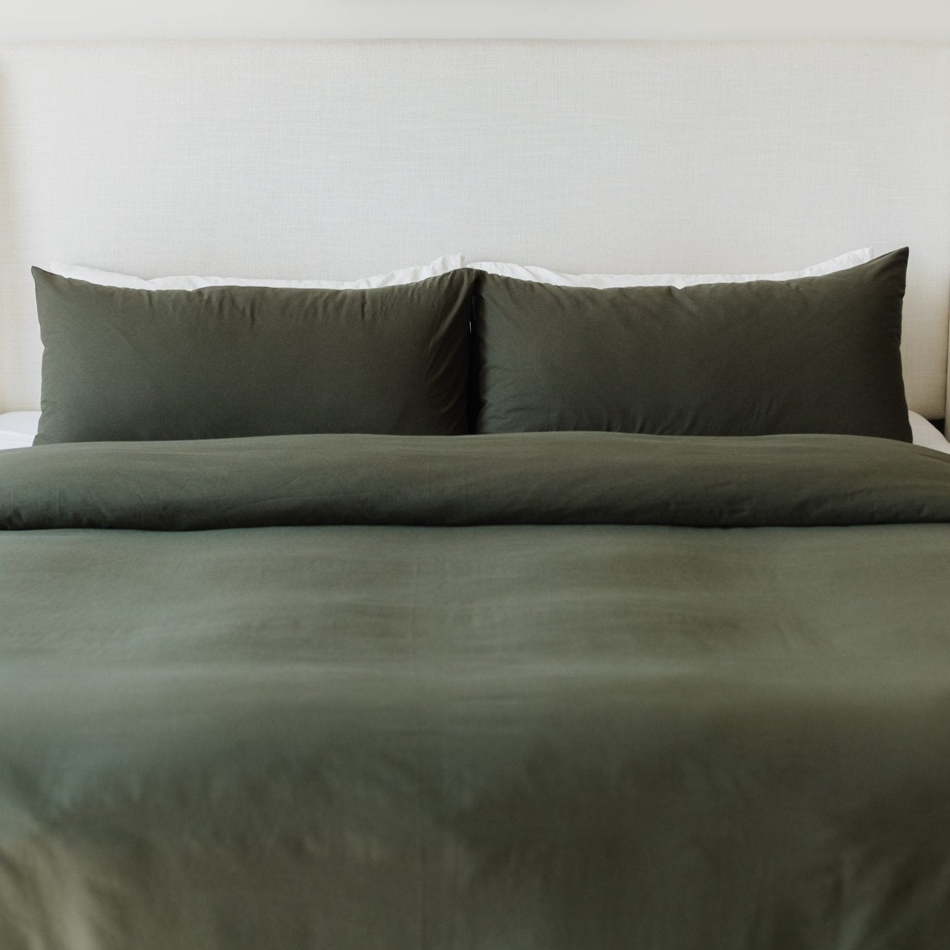 Olive-colored king duvet cover set with two matching pillowcases on a made bed.