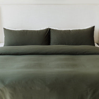 Olive-colored king duvet cover set with two matching pillowcases on a made bed.