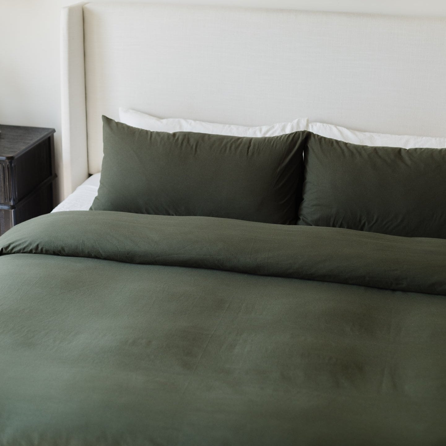 Olive-green duvet cover and two matching pillowcases on a bed with white sheets.