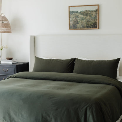 Olive-green king duvet cover with matching pillowcases and insert on bed with white headboard.
