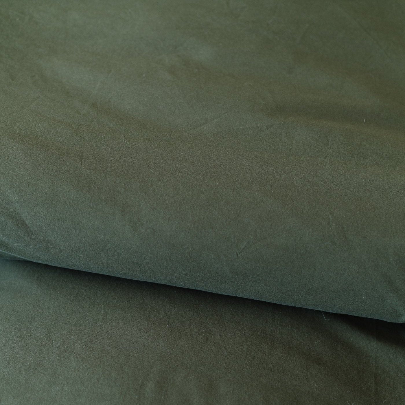 Folded olive-colored duvet cover showing the fabric texture and natural wrinkles.
