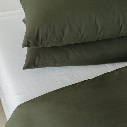 Olive green duvet cover with two matching pillowcases on a white sheet-covered bed.