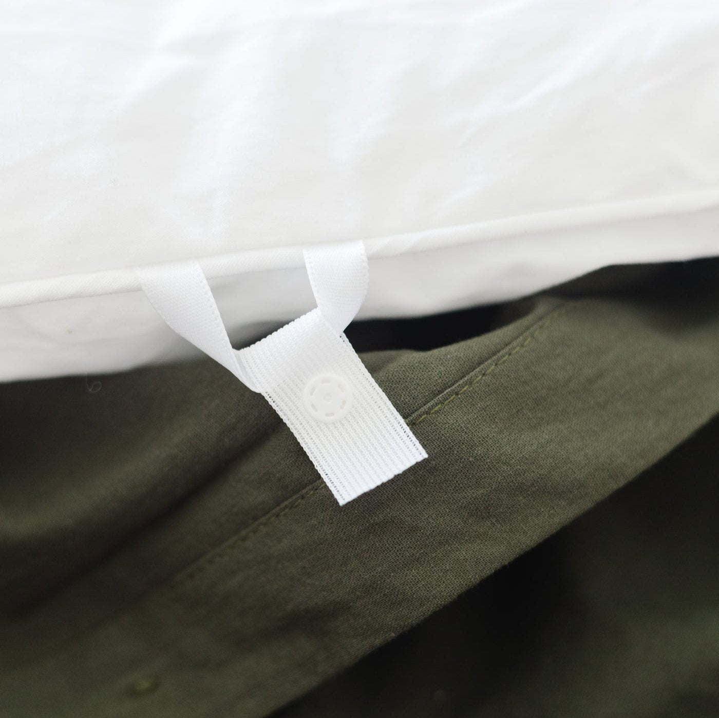 Olive duvet cover with white interior binding and corner tie detail on king-size bedding.