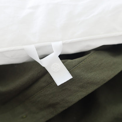 Olive duvet cover with white interior binding and corner tie detail on king-size bedding.