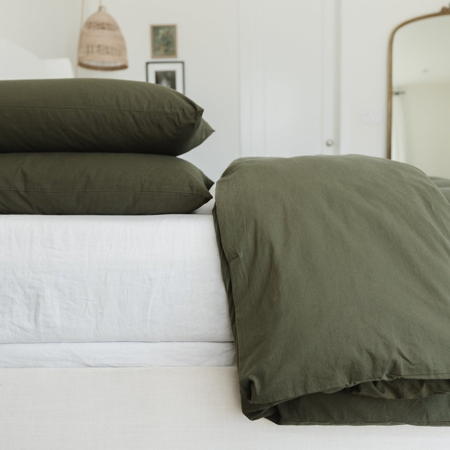 Olive duvet cover with white insert and two matching pillows on made bed.