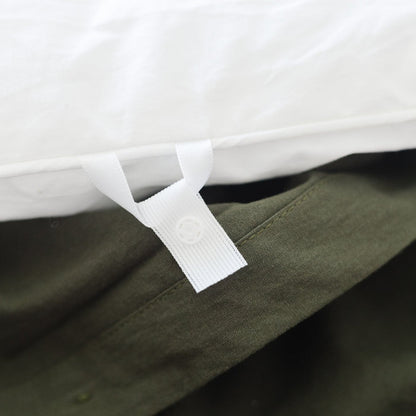 Olive green duvet cover with white ties and white duvet insert visible underneath on bed.