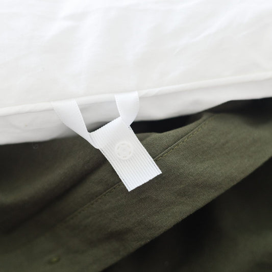Olive green duvet cover with white ties and white duvet insert visible underneath on bed.