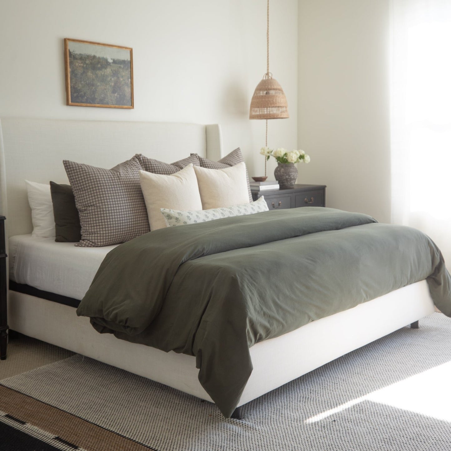 King-size bed with olive green duvet cover, white sheets, and coordinating patterned pillows.