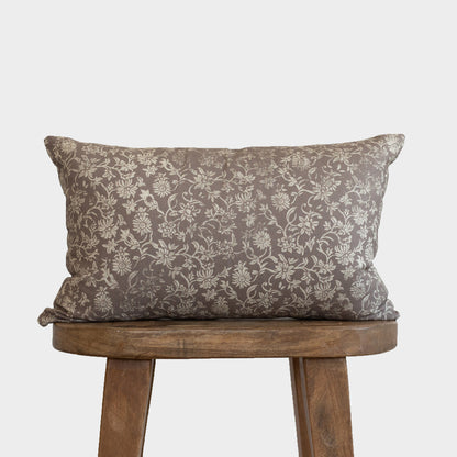 Gray floral patterned lumbar pillow with cream damask design displayed on a wooden stool.