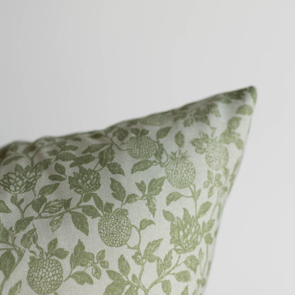 Green and white pillow with botanical print featuring fruits and leafy stems.