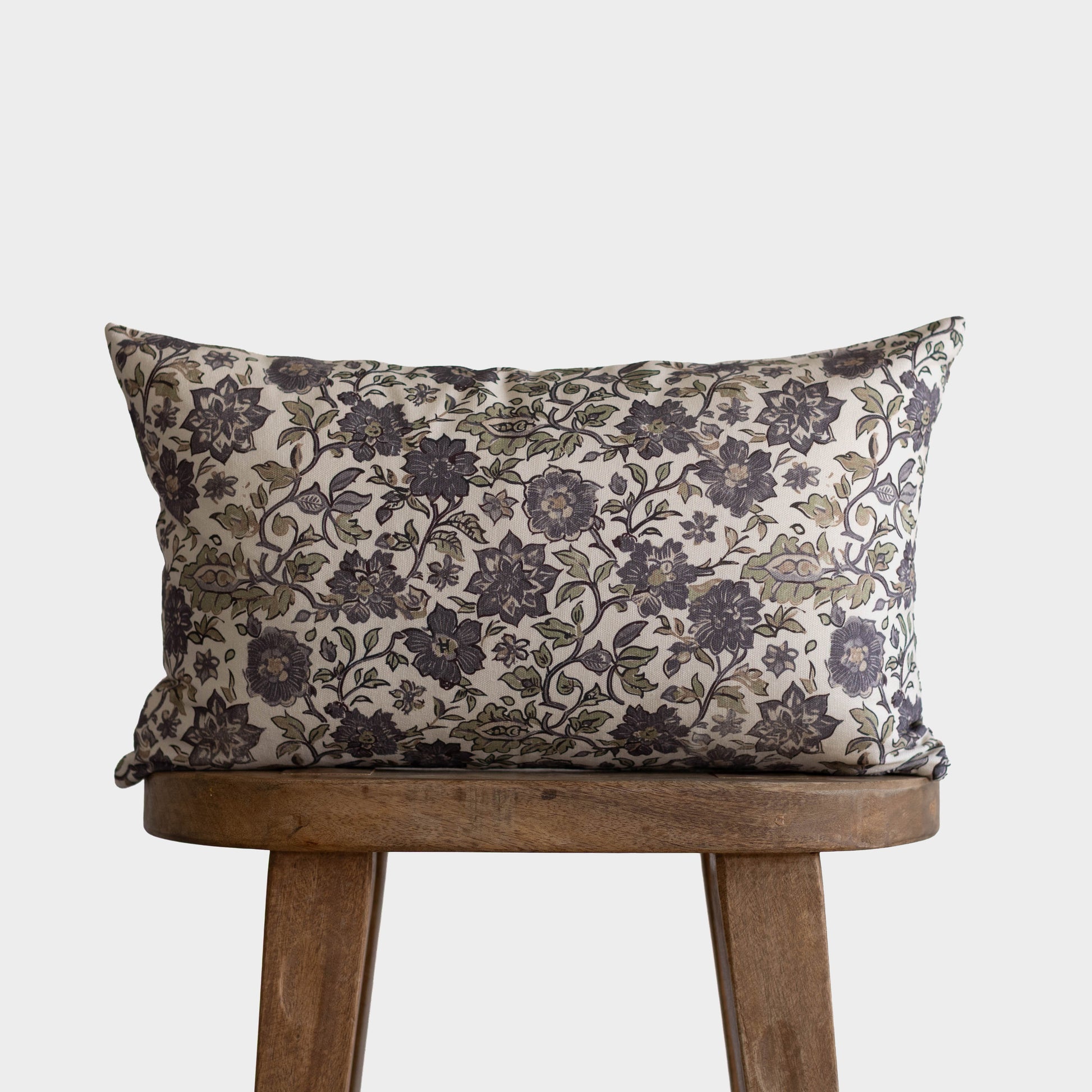Rectangular pillow with black and gray floral pattern on cream background, displayed on wooden chair.