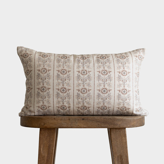 Cream and taupe striped throw pillow with floral botanical pattern, displayed on wooden stool.