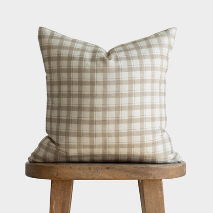 Beige and cream plaid pillow cover displayed on wooden stool.