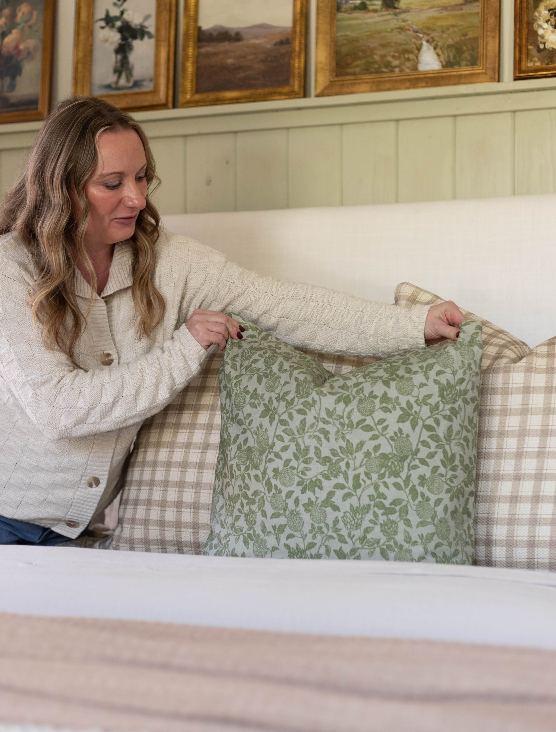 Green damask patterned pillow with cream linen backing displayed on a neutral sofa.