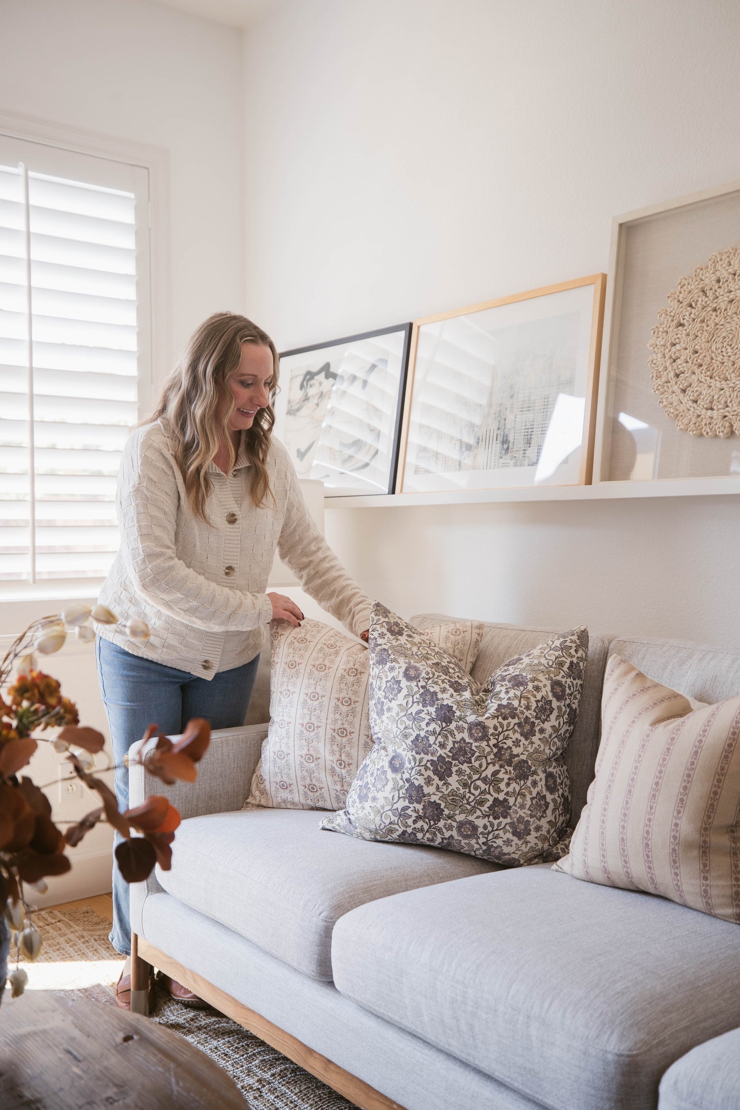 Light gray upholstered sofa with wooden frame, styled with patterned throw pillows in neutral tones.