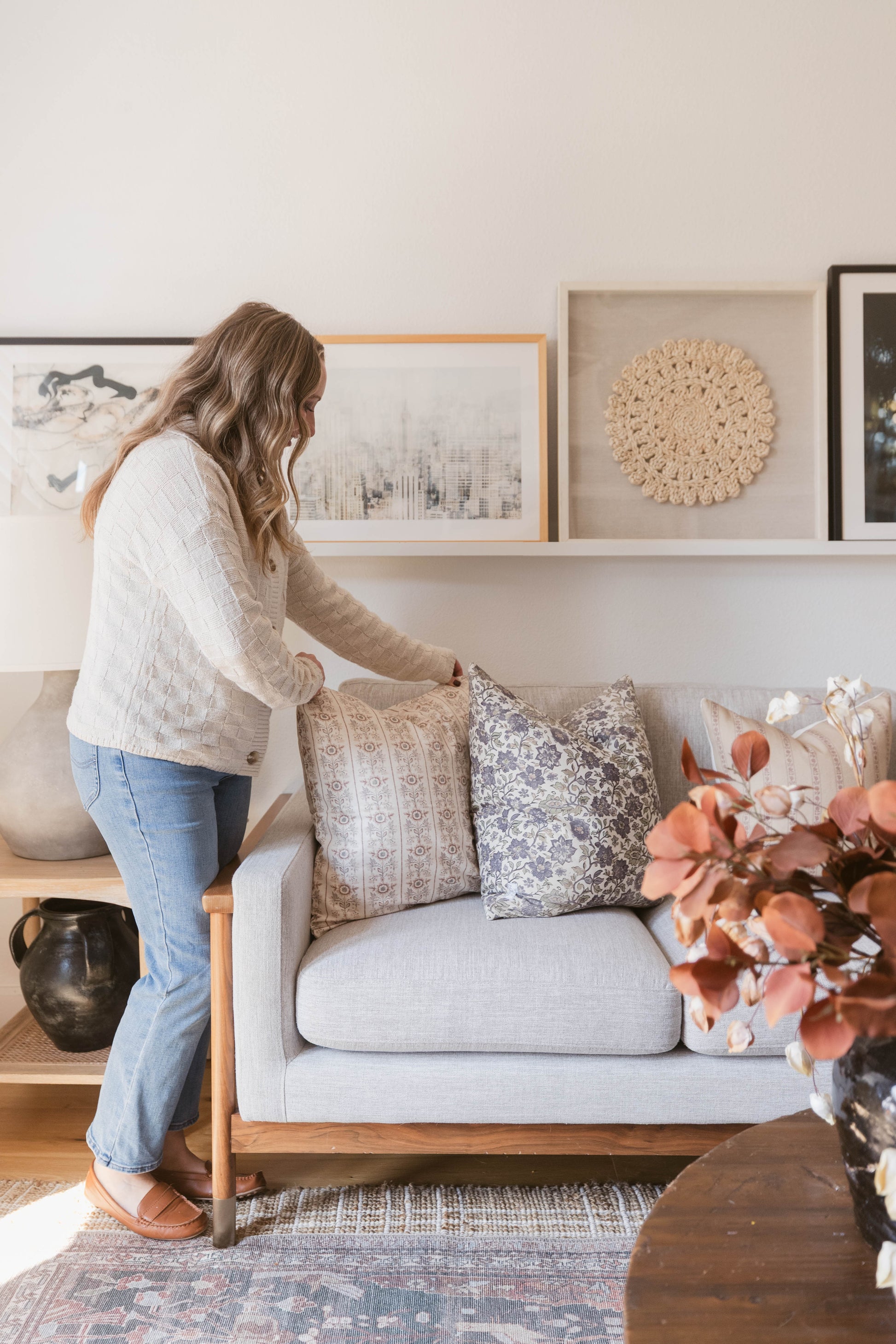 Light gray upholstered sofa with wooden frame and decorative patterned throw pillows in a living room setting.