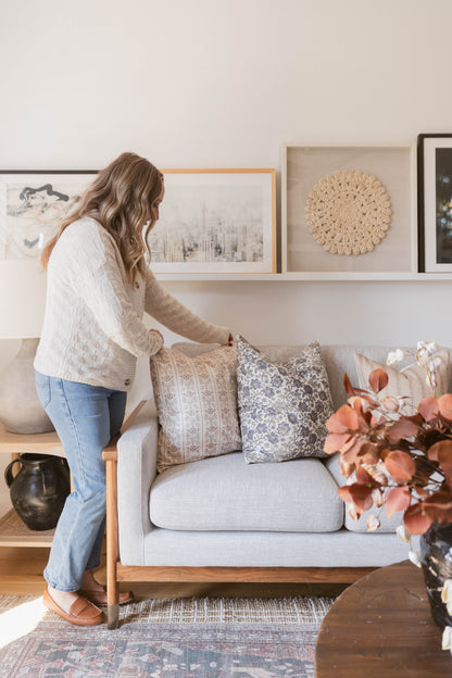 Light gray upholstered sofa with wooden frame and decorative patterned throw pillows in a living room setting.
