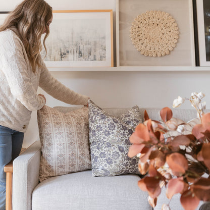 Cream crocheted circular wall hanging displayed on white shelf above beige sofa with decorative pillows.