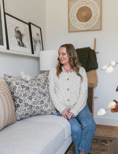 Four framed prints displayed on walls above a sofa with decorative pillows and blankets in a living room setting.