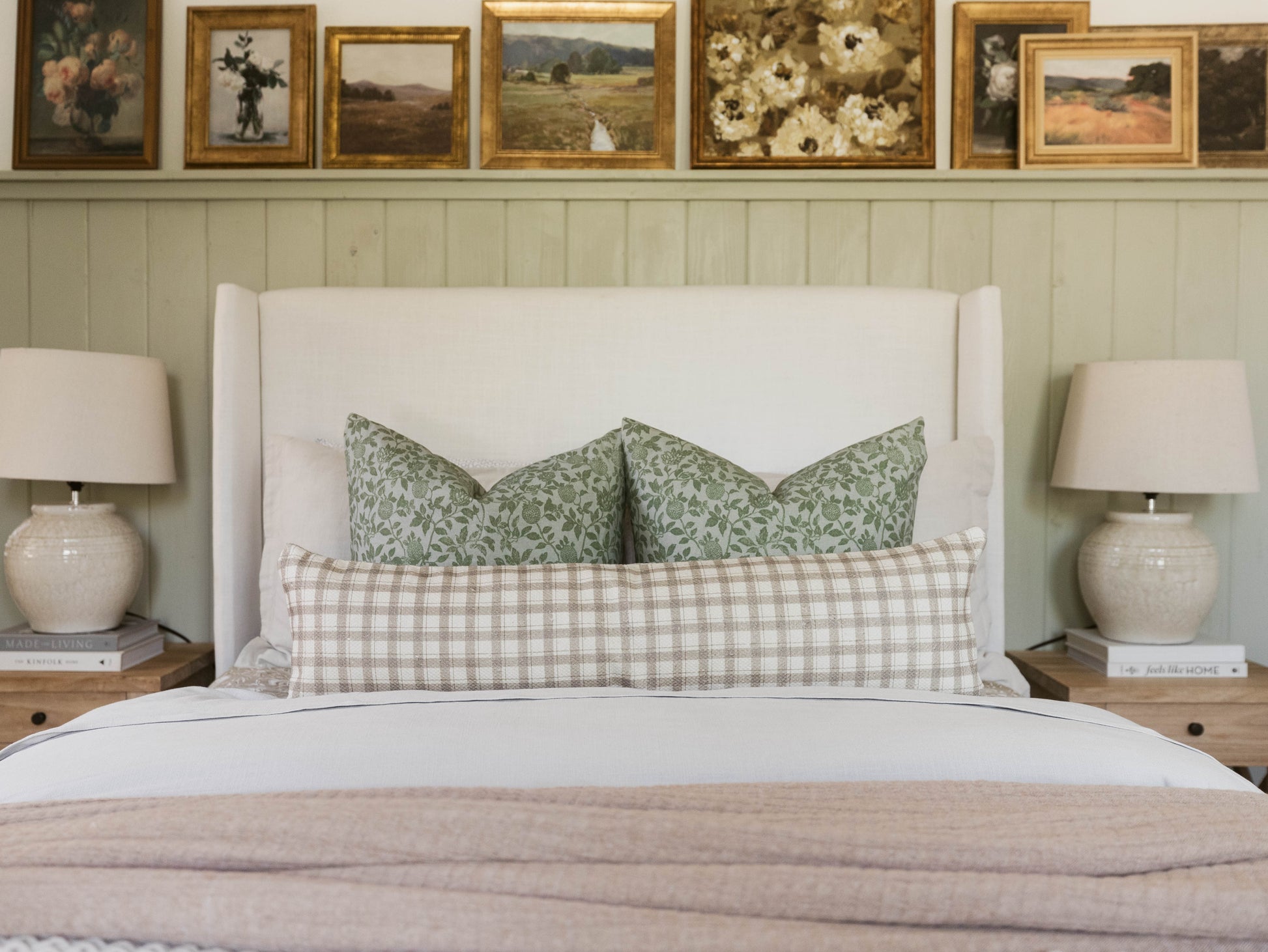 Beige and white checkered cotton throw pillow on bed with green patterned pillows.