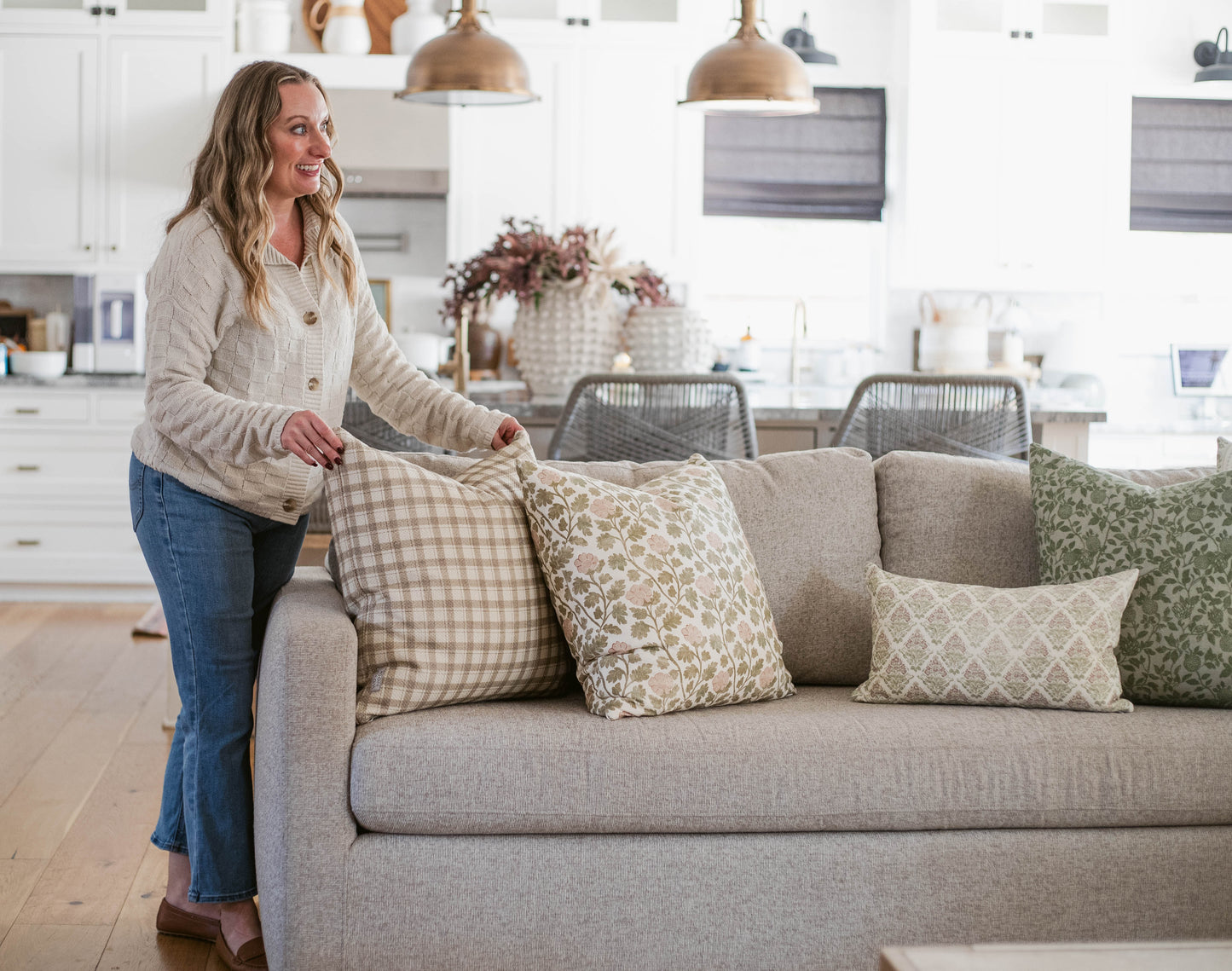 Five decorative pillows in neutral tones with geometric and plaid patterns arranged on a gray sofa.
