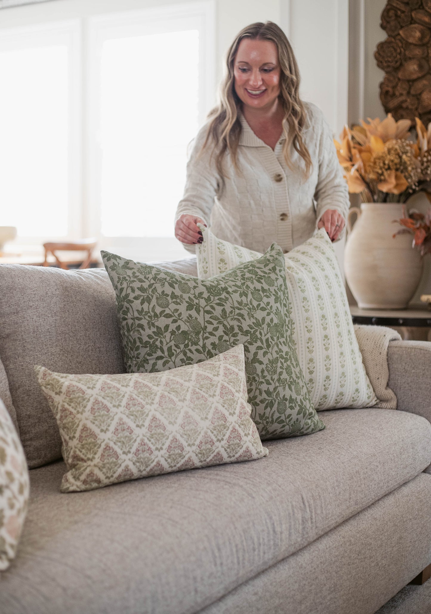 Five decorative pillows in various sizes with geometric and floral patterns displayed on a gray sofa.
