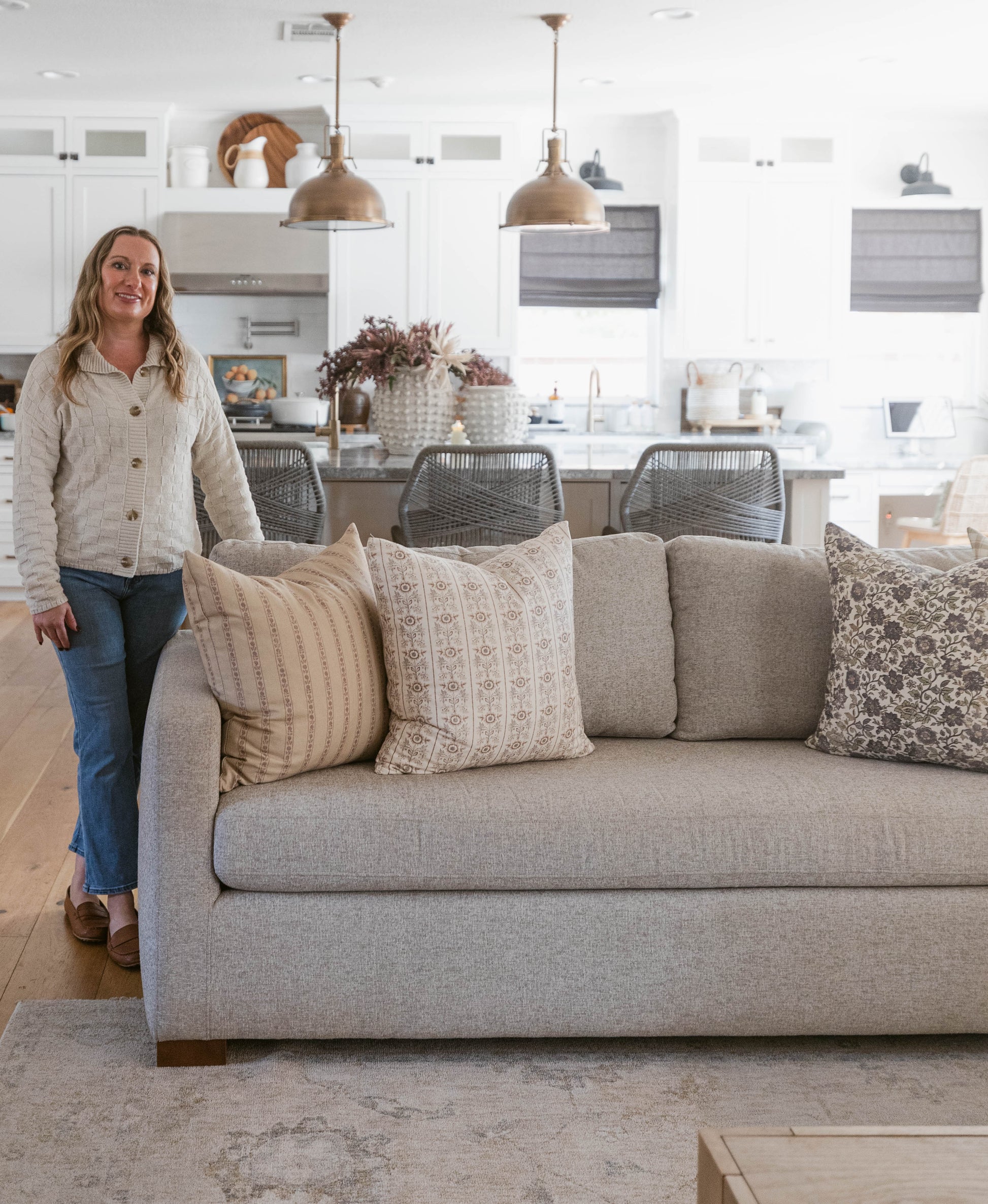 Four decorative throw pillows in various patterns displayed on a gray upholstered sofa in a living room setting.
