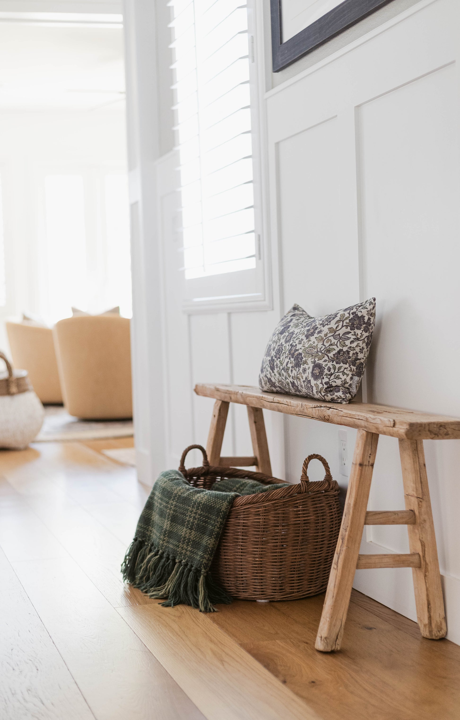 Hattie pillow with black floral pattern displayed on wooden bench in bright entryway.