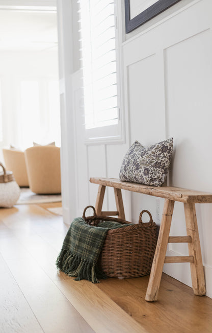 Hattie pillow with black floral pattern displayed on wooden bench in bright entryway.