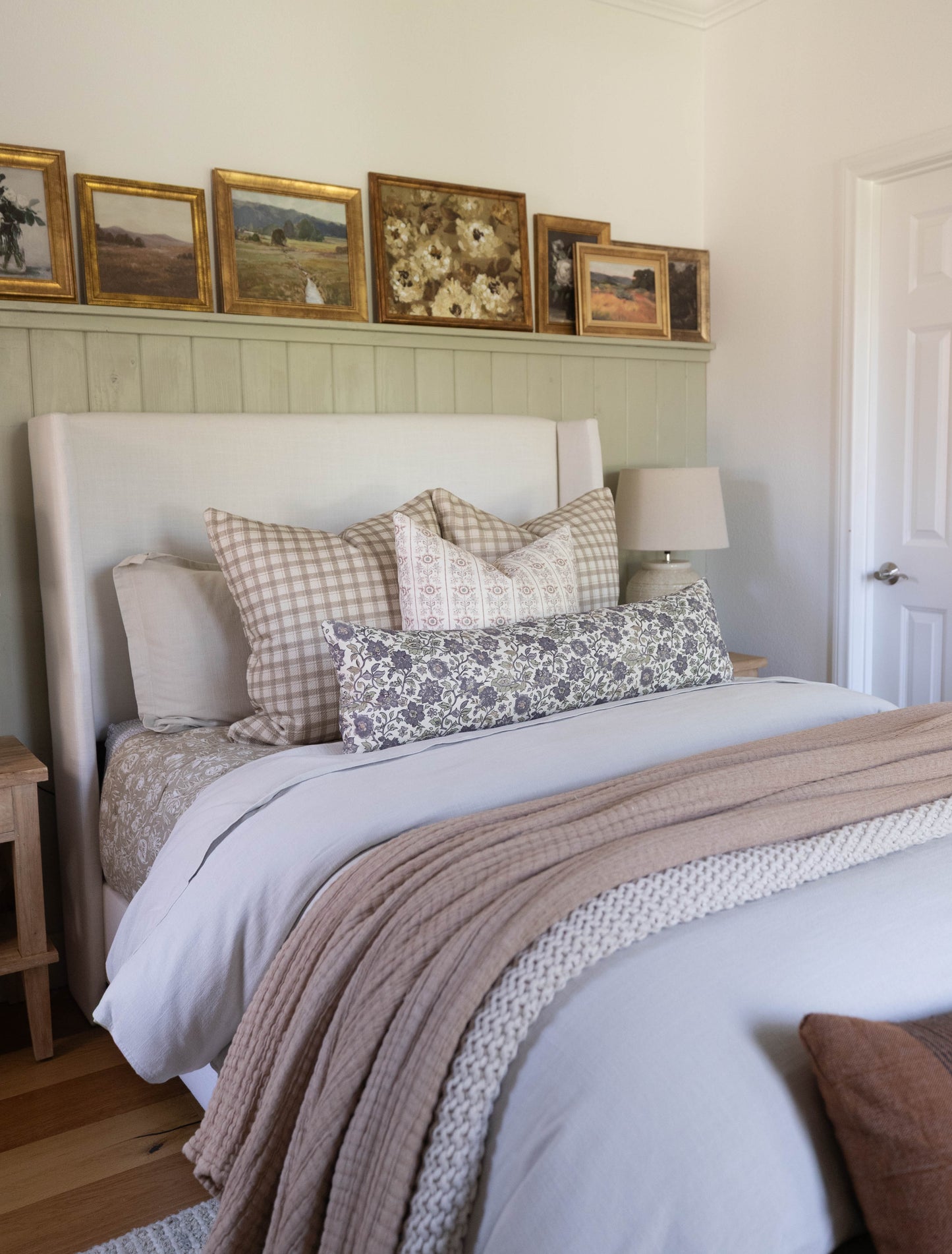 White upholstered bed headboard with wingback design in bedroom setting with bedding and pillows.