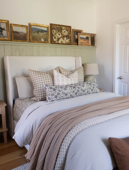White upholstered bed headboard with wingback design in bedroom setting with bedding and pillows.