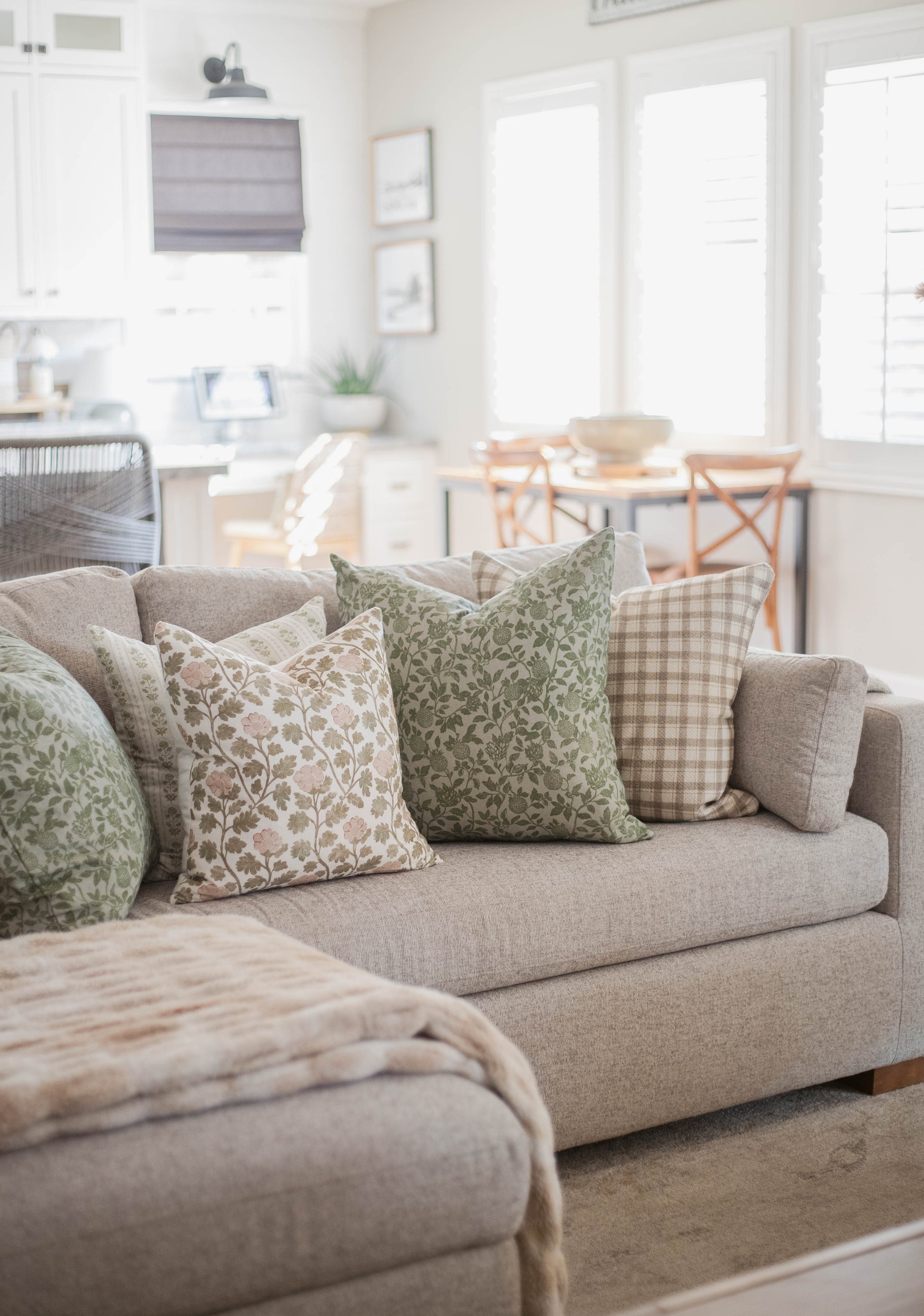 Beige cotton throw pillow with thick weave texture displayed on a gray upholstered sofa with patterned decorative pillows.