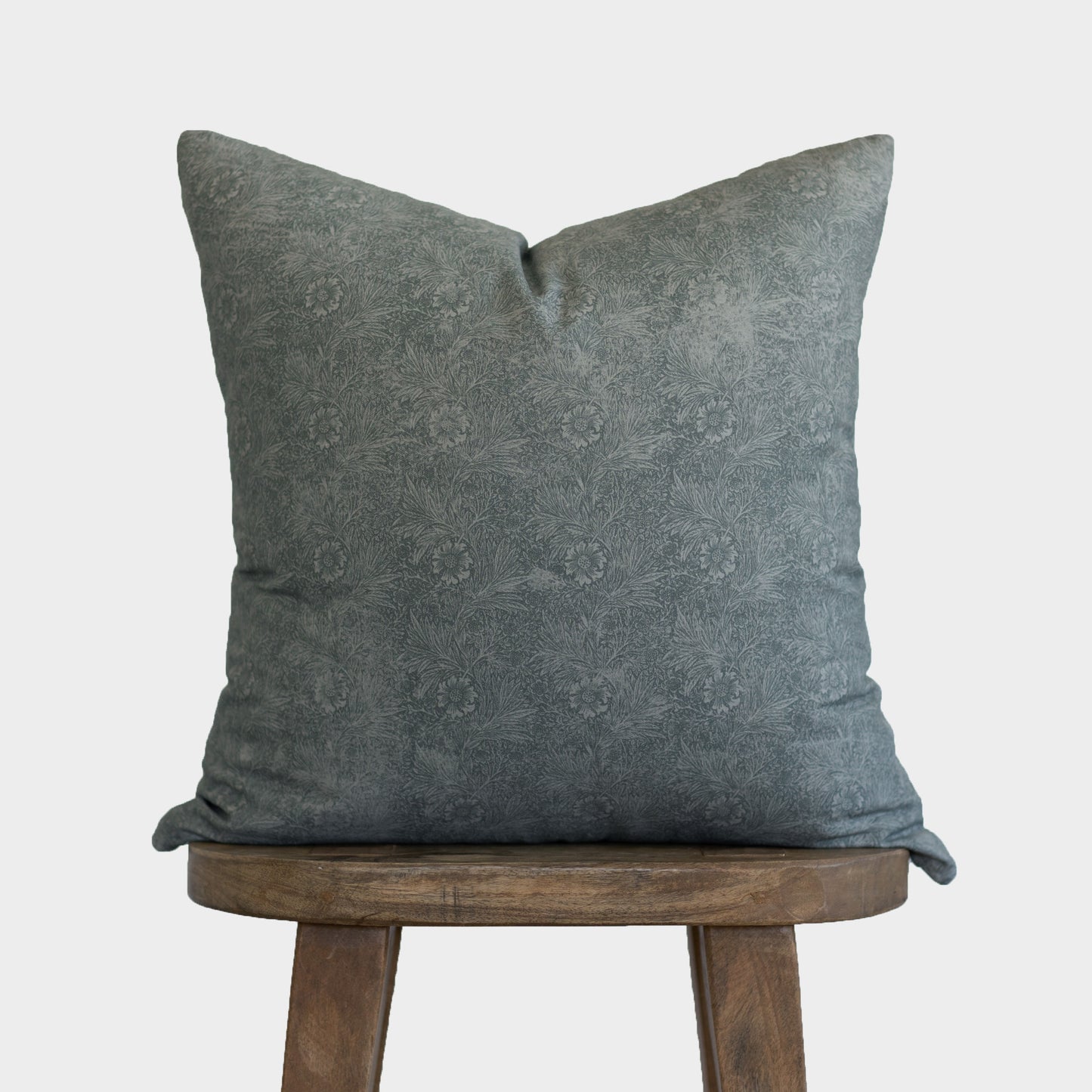 Gray damask patterned pillow cover displayed on a wooden stool against a white background.