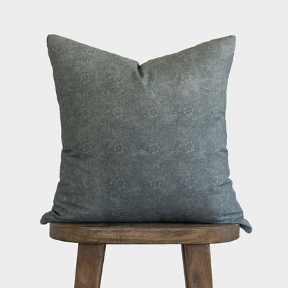 Gray damask patterned pillow cover displayed on a wooden stool against a white background.