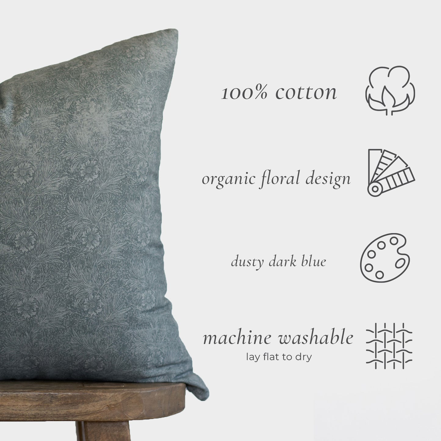Dusty dark blue cotton pillow with organic floral design, displayed on wooden stool.