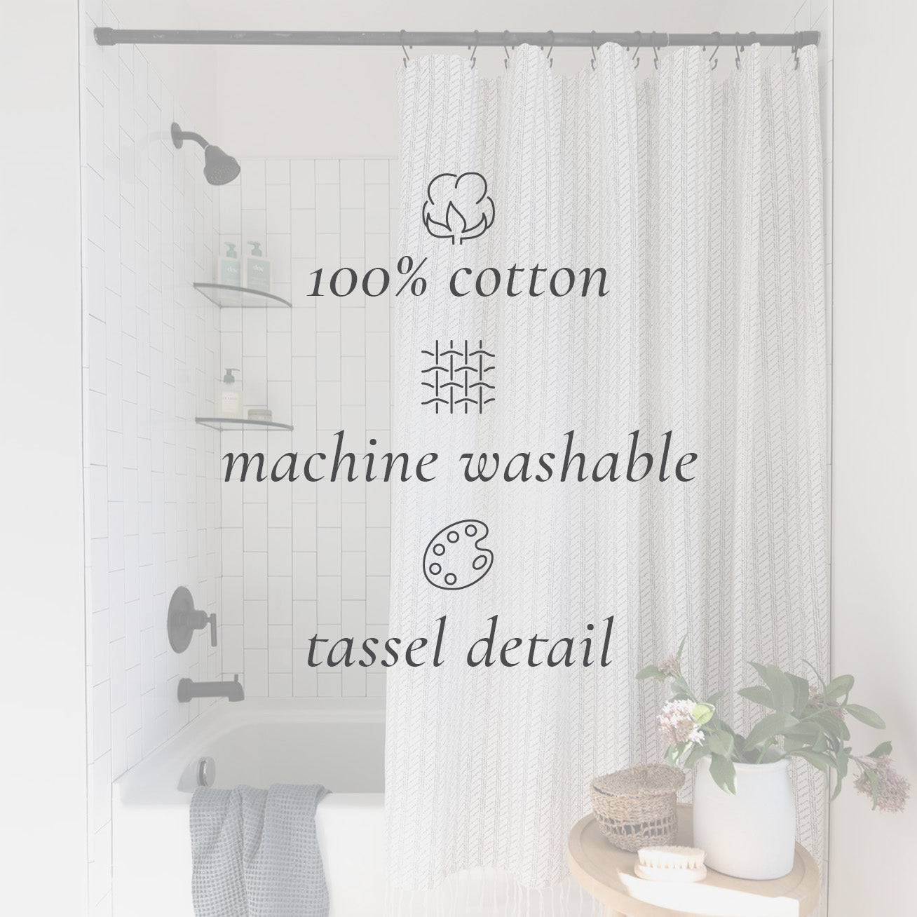 Cream cotton shower curtain with woven texture and tassel trim hung on gray rod in white tile bathroom.
