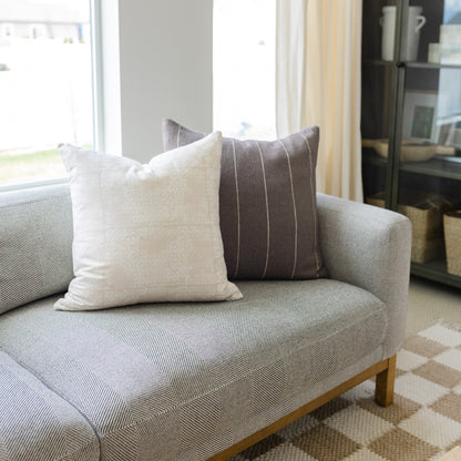 Cream and charcoal striped throw pillow displayed on beige upholstered chair.