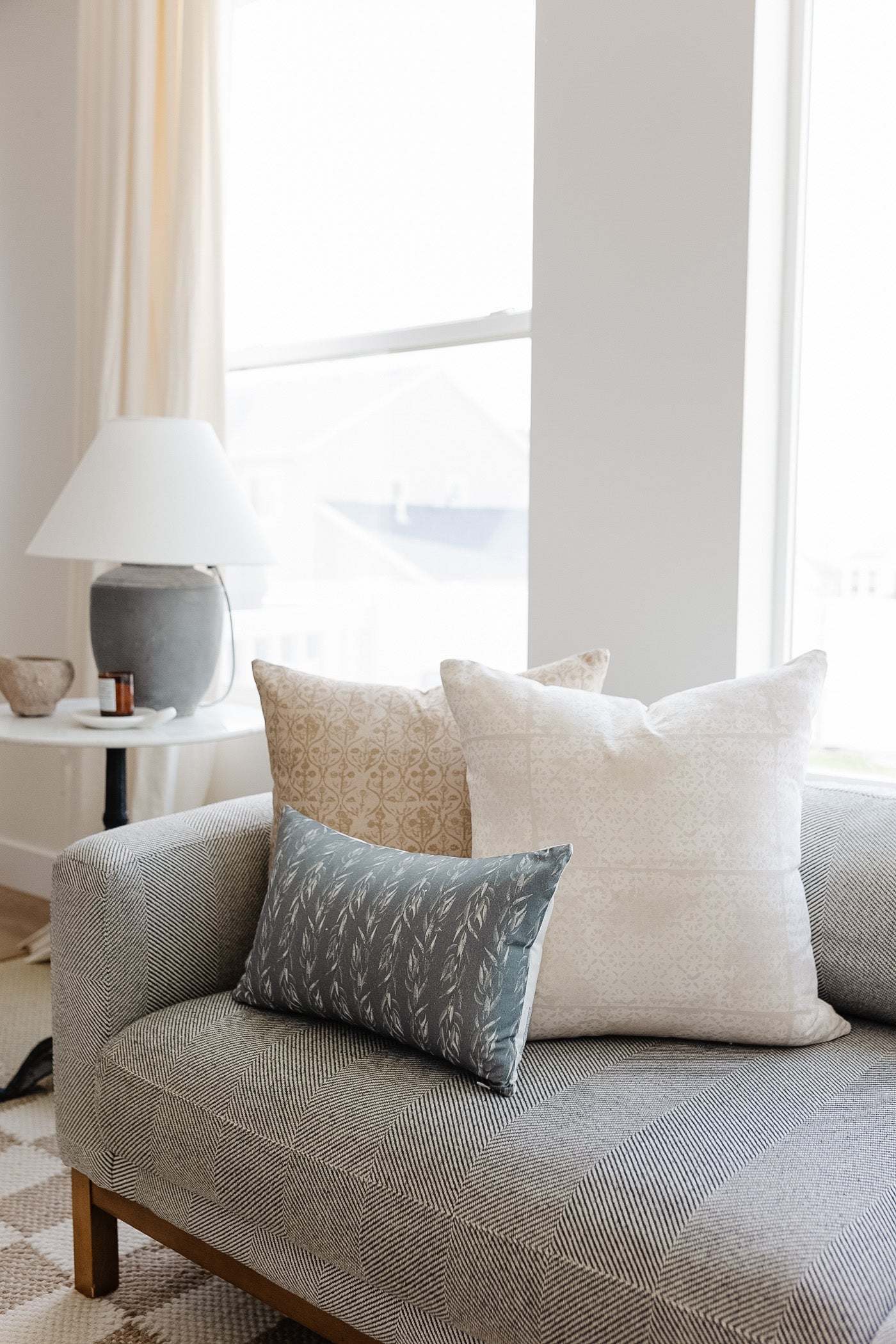 Sage Leaves lumbar pillow with leaf pattern in gray-blue on gray upholstered sofa with coordinating pillows.