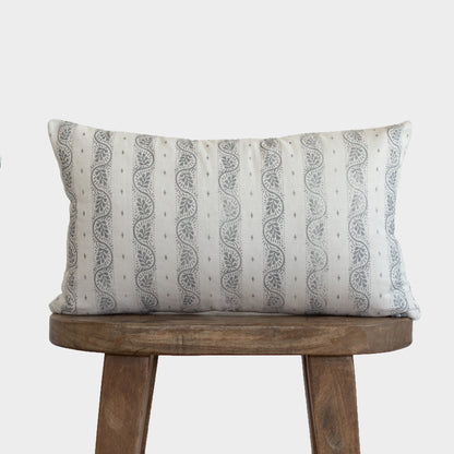 Rectangular lumbar pillow with cream background and gray vertical striped pattern with leaf motifs, displayed on wooden stool