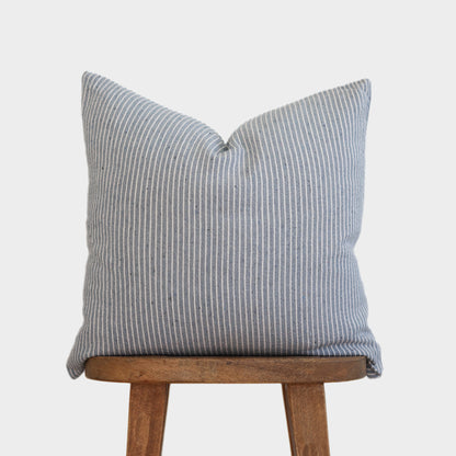 Blue and white vertical striped pillow displayed on wooden chair legs.