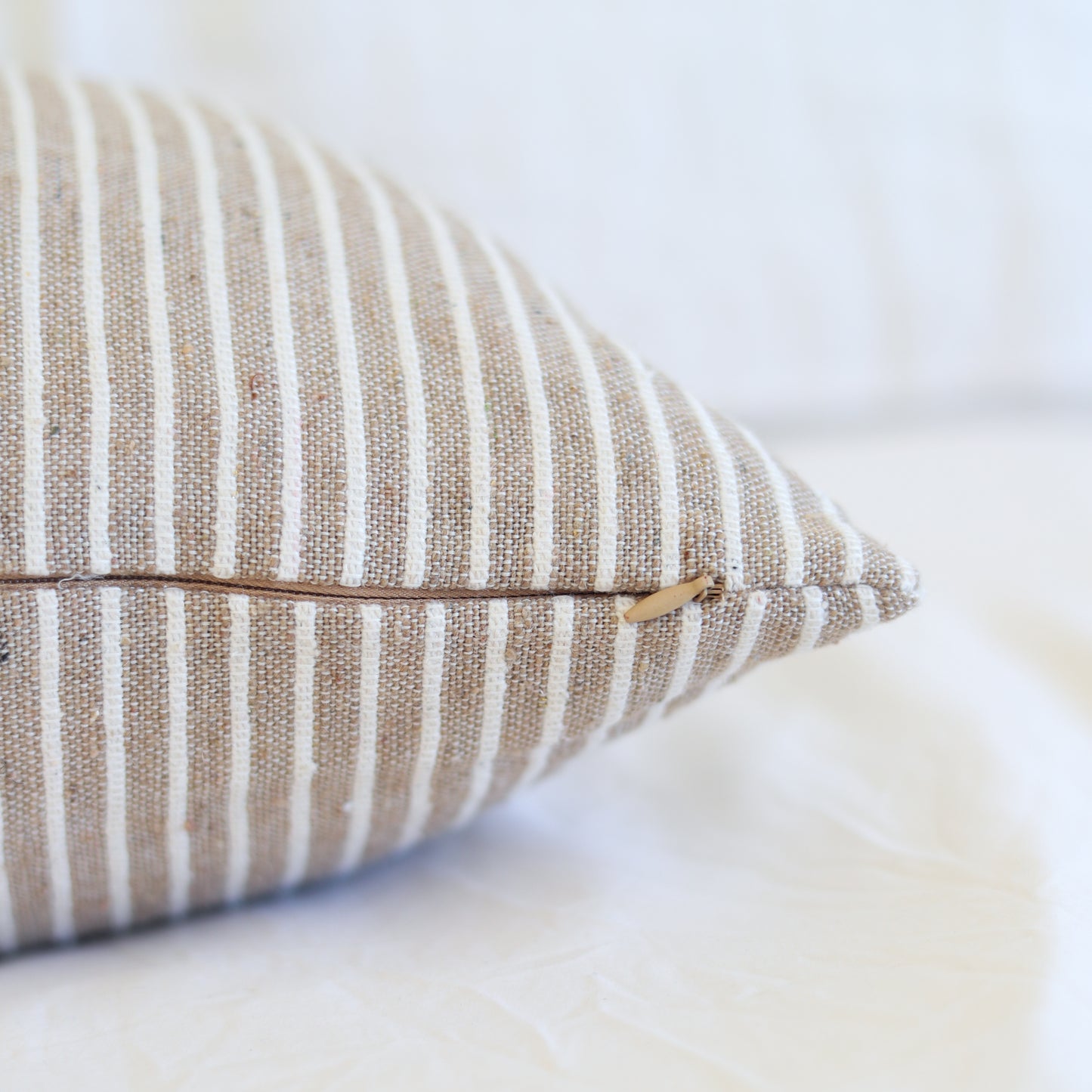 Tan and white striped lumbar pillow with zipper closure detail.