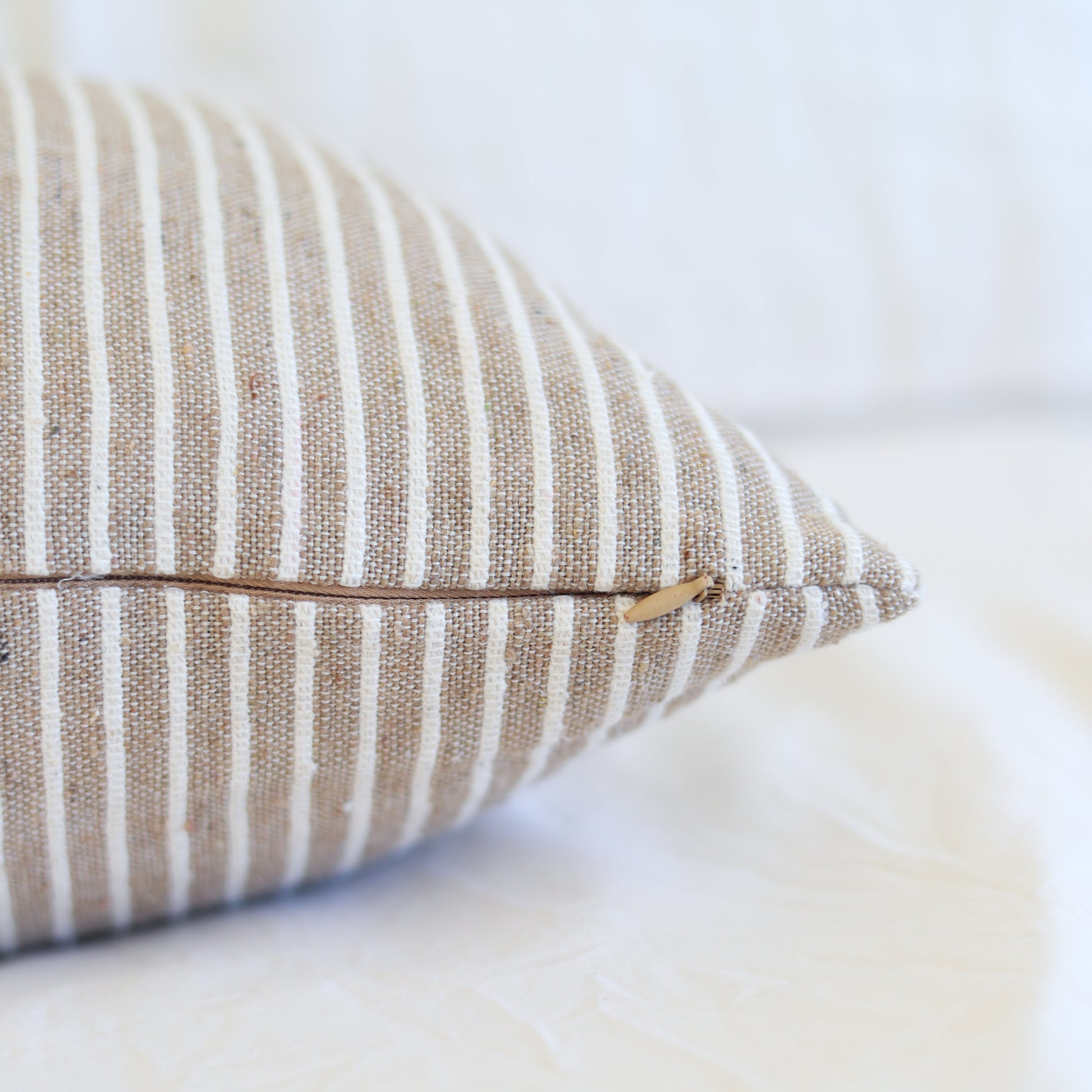 Tan and white striped lumbar pillow with zipper closure detail.