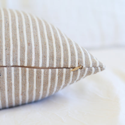 Tan and white striped lumbar pillow with zipper closure detail.